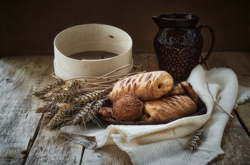 A rustic setup featuring pastries and wheat on a wooden table, exuding a cozy and vintage vibe.